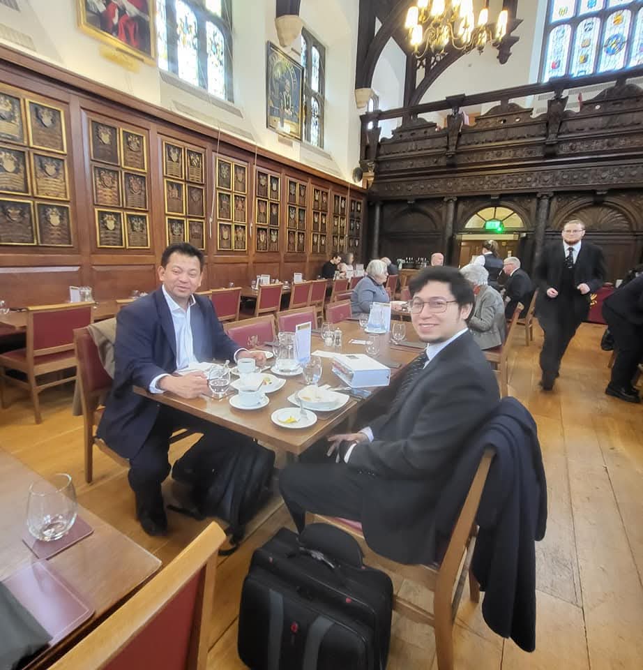 Seated in an historic armorial-panelled dining hall.