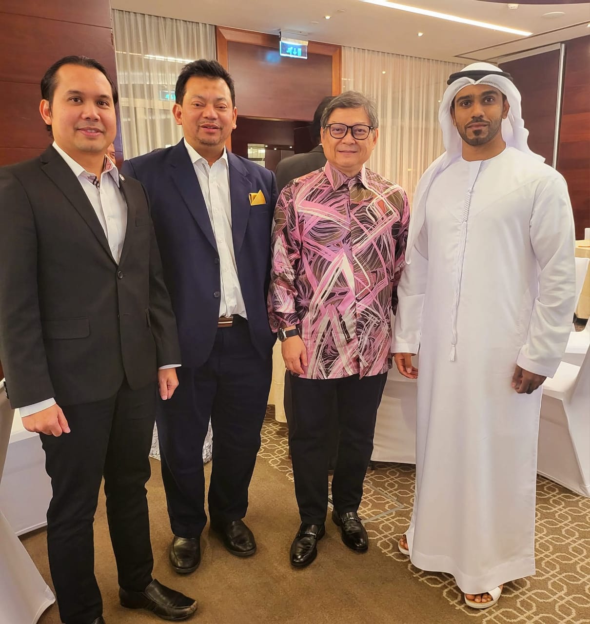 With counterparts, including a host in Gulf national dress, at a function room.