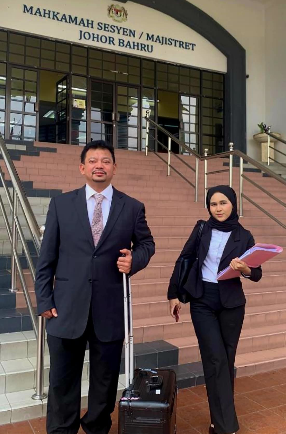 Counsel and a junior colleague carrying case files on the steps of the Johor Bahru Sessions Court.