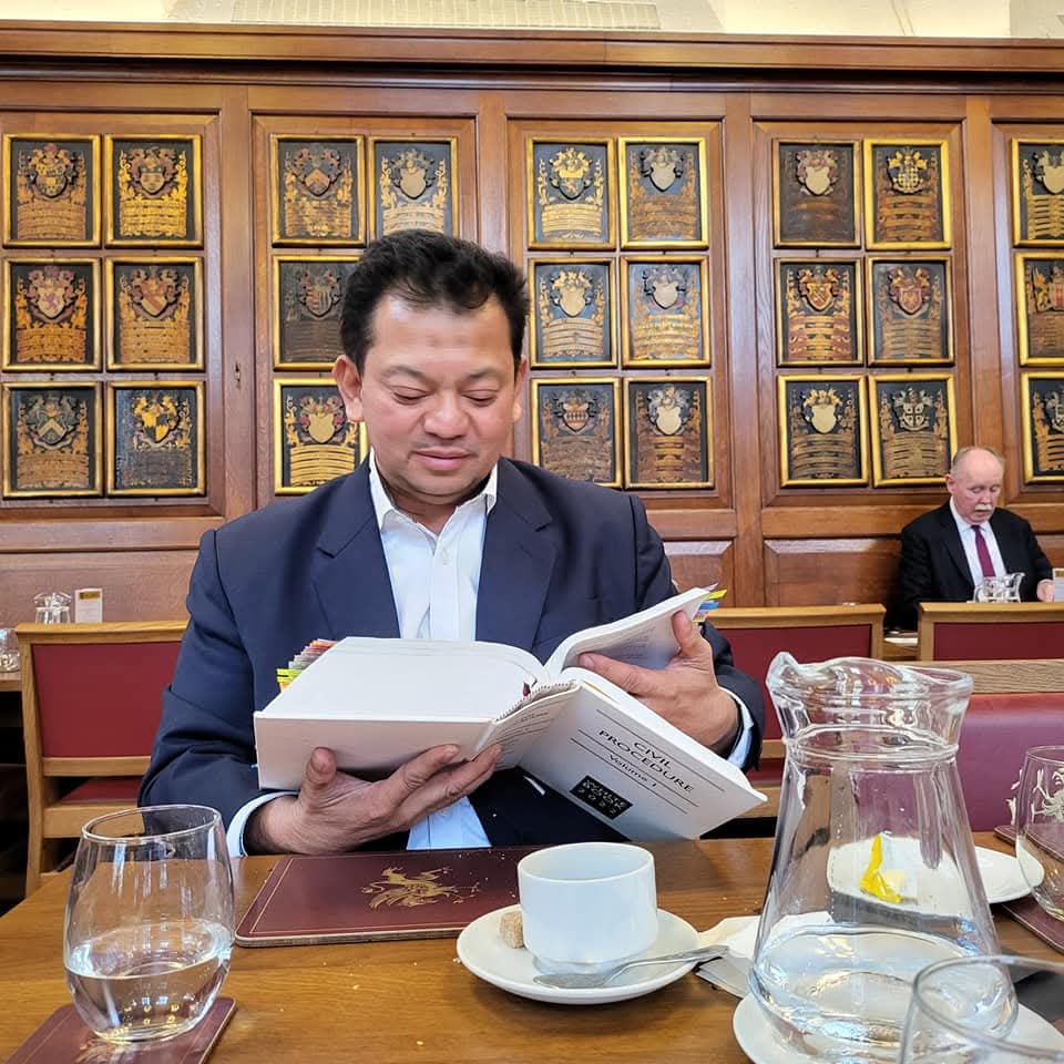 Counsel consulting the White Book on civil procedure in an Inn of Court hall.